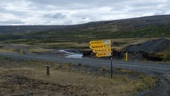 Highland landscape with dirt road and arrow signs, Iceland — Stock Photo