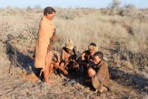 Namibia, Ghanzi Trailblazers, Safari, Bushwalk, Bushmen, Bushmen se calientan en el fuego - foto de stock