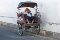 Sleeping rickshaw driver on city street, Jogyakarta, Java, Indonesia — стоковое фото
