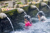 Indonesia, Bali, Gianyar, Mujeres rezando en el agua del templo hindú Pura Tirta Empul - foto de stock
