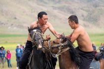 AK SAY, ISSYK-KUL REGION, KYRGYZSTAN - 12 de agosto de 2017: Hombres luchando a caballo, Juegos Nómadas - foto de stock