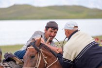 OSH REGION, KYRGYZSTAN - JULY 22, 2017: Men wrestling on horseback during nomad games — Stock Photo