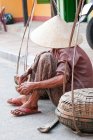 Vietnam, Old lady sitting at street and hiding behind conical hat — Stock Photo