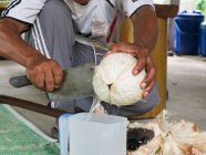Thailand, Tambon Khuekkhak, man with knife opening coconut — Stock Photo
