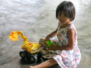 Menina brincando com escavadeira de brinquedos no chão, Phang nga, Tailândia — Fotografia de Stock