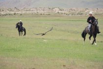 AK SAY, ISSYK-KUL REGION, KIRGYZSTAN - 12 AGOSTO 2017: Prestazione dimostrativa di cacciatori di aquile, uomini a cavallo — Foto stock