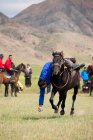 AK SAY, ISSYK-KUL REGION, KYRGYZSTAN - AUGUST 12, 2017: skill exercise in gallop, nomad games, local men riding horses — Stock Photo