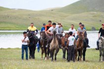REGIONE OSH, KIRGYZSTAN - 22 LUGLIO 2017: Giochi nomadi, uomini a cavallo, paesaggio montano con lago sullo sfondo — Foto stock