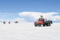 Bolivia, Departamento de Potosi, Nor Lopez, deserto del sale a Uyuni, Gente che cavalca jeep attraverso il paesaggio desertico — Foto stock