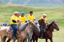 OSH REGION, KYRGYZSTAN - 22 de julio de 2017: Nomadgames, goat polo, yellow team, men riding on horses - foto de stock