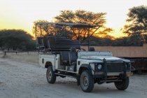 Namibia, Okapuka Rancho, Safari, Game Drive, Safari Jeep estacionado en la carretera al atardecer - foto de stock