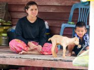 Madre con niño y cabra bebé en la aldea de Talaenok, Tailandia - foto de stock