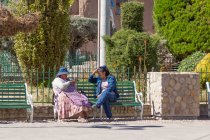 Dos mujeres locales hablando en el banquillo, Puno, Perú - foto de stock