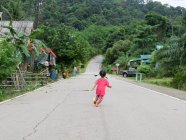 Menina correndo na estrada vazia na rua em Talaenok, Tailândia — Fotografia de Stock