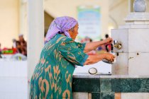 Old woman pouring water in kettle in big bazaar, Buxoro, Uzbekistan — Stock Photo