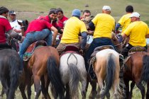 Región OSH, KYRGYZSTAN - 22 de julio de 2017: Nomadgames, men on horses, participants in goat polo, rear view - foto de stock