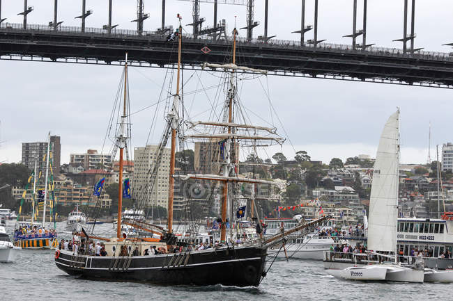 Австралия, Сидней, корабли у моста в городском порту, городской пейзаж на заднем плане — стоковое фото