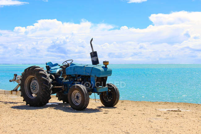 Острова Кука, Айтутаки, гавань, трактор, припаркованный рядом с береговой линией голубого океана — стоковое фото