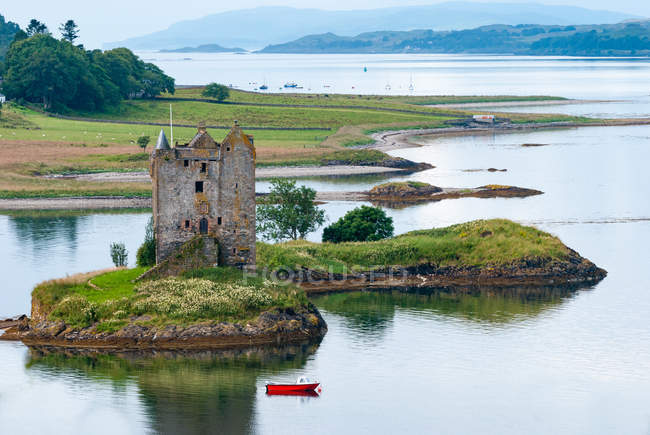 United Kingdom, Scotland, Argyll and Bute, View of Castle Stalker on small rocky tidal island in the Loch Lake and red boat passing by — Stock Photo