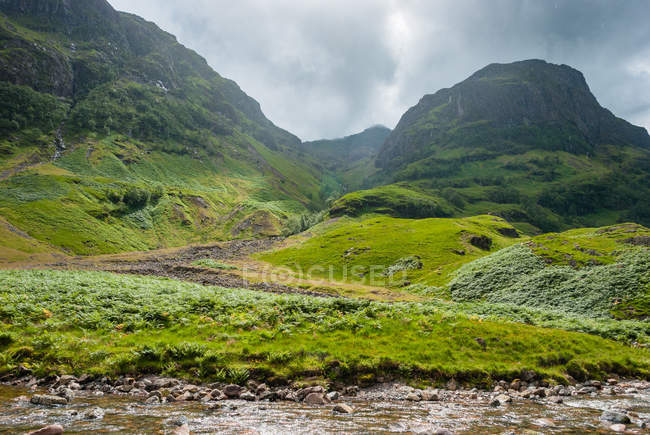 Reino Unido, Escócia, Highland, Ballachulish, Glencoe paisagem de montanhas verdes com pequeno riacho — Fotografia de Stock