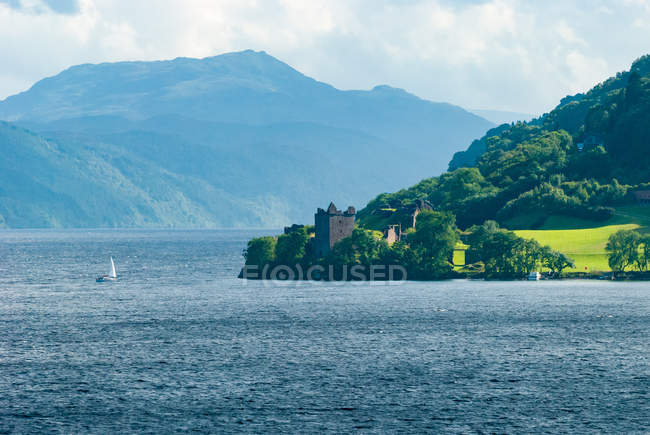 United Kingdom, Scotland, Highland, Inverness, Urquhart Castle, Loch Ness Castle by lake with sailing boat and mountains on background — Stock Photo