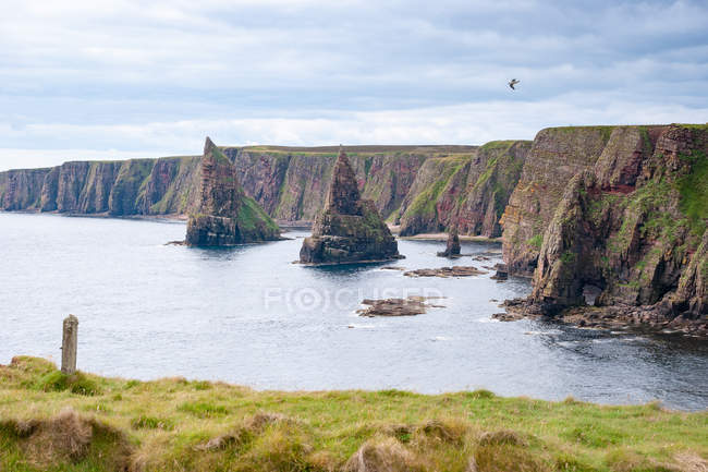 Reino Unido, Escocia, Highland, Wick, Duncansby Head, Duncansby Head con formaciones rocosas escarpadas y guiños rocosos - foto de stock