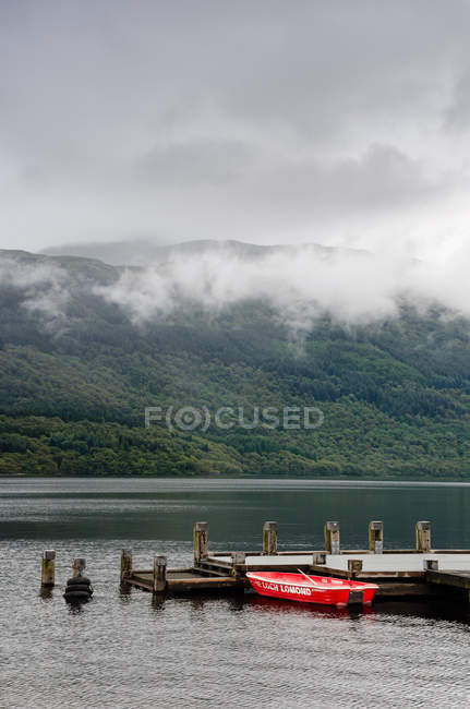 United Kingdom, Scotland, Argyll and Bute, Arrochar, Loch Lomond lake scenic landscape and boat moored by pier — Stock Photo
