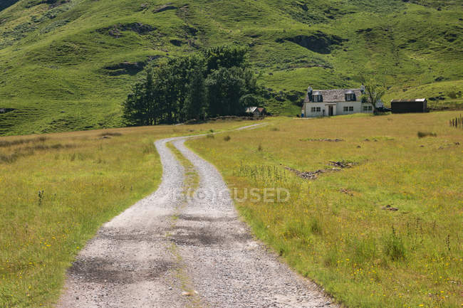Reino Unido, Escocia, Highland, Ballachulish, camino a la casa en Glencoe lugar a través de verdes colinas - foto de stock