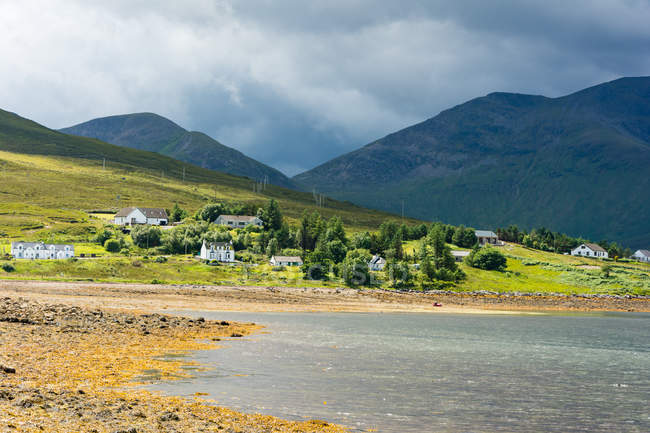 Reino Unido, Escócia, Highland, Ilha de Skye, Loch Ainort, pequena aldeia por lago de montanha — Fotografia de Stock