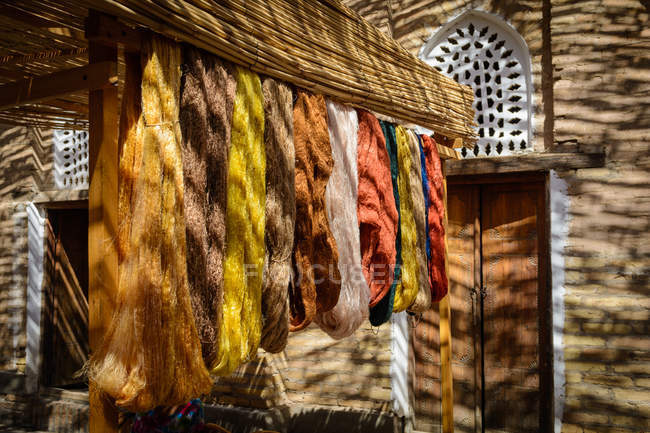 Ouzbékistan, Province de Xorazm, Xiva, soie naturelle teinte accrochée à des crochets — Photo de stock