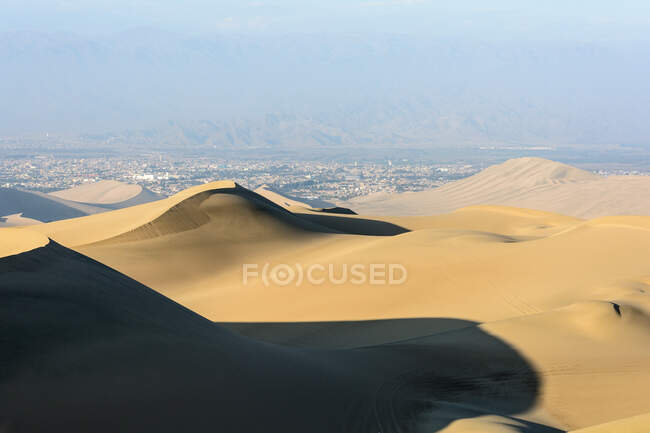 Hohe Sanddünen mit Stadt in der Ferne, Huacachina, Ica, Peru — Stockfoto
