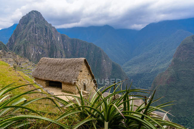 Perú, Cusco, Urubamba, Machu Picchu es Patrimonio de la Humanidad por la UNESCO, pequeña cabaña en la ladera de la montaña - foto de stock
