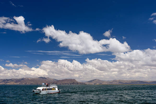 Перу, Пуно, поездка на лодке на Урос, живописный вид с белой лодкой на озере — стоковое фото