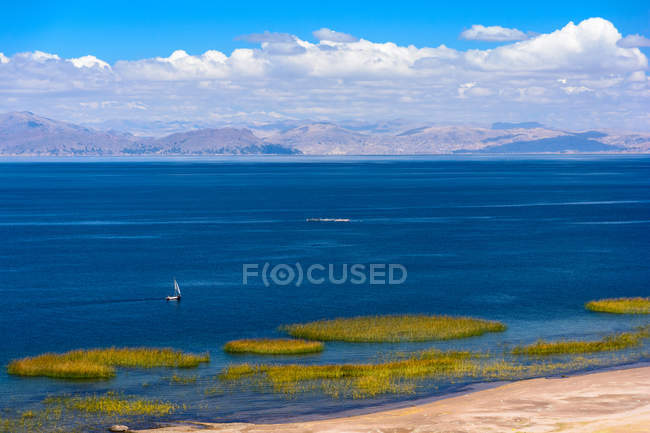 Perú, Puno, viaje en barco a los Uros, vista aérea panorámica con velero en el lago con montañas en el fondo - foto de stock