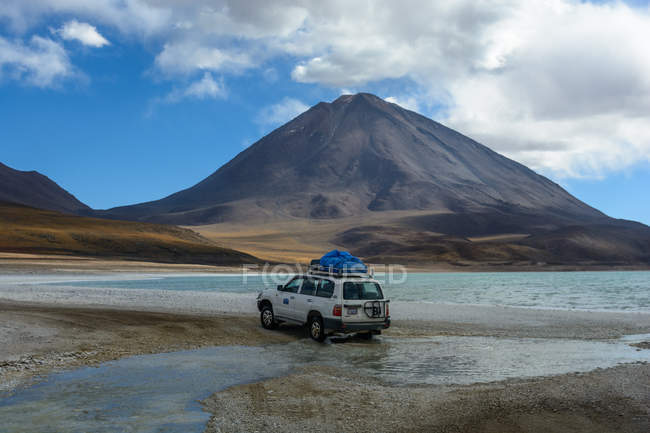 Paisagem deserta com carro de jipe indo para o vulcão Licancabur na fronteira entre Bolívia e Chile — Fotografia de Stock