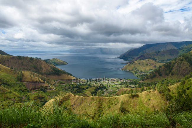 Indonesia, Sumatera Utara, Kabubaten Karo, Lago Toba vista aérea con paisaje de montañas cubiertas de hierba - foto de stock