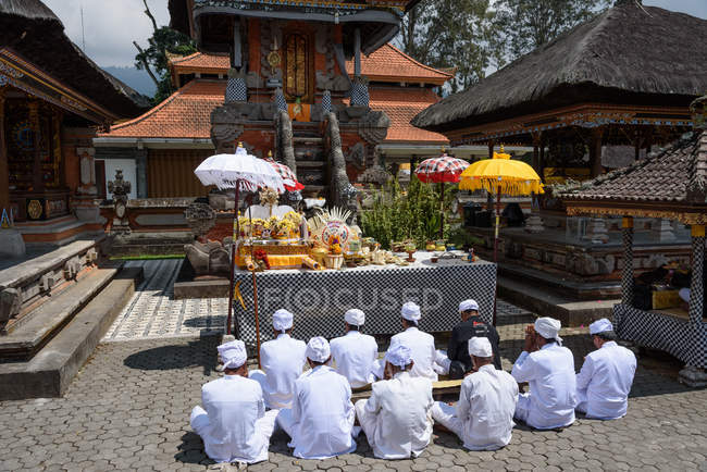 Indonesia, Bali, Kaban Tabanan, Hombres con ropa blanca rezando junto al templo - foto de stock
