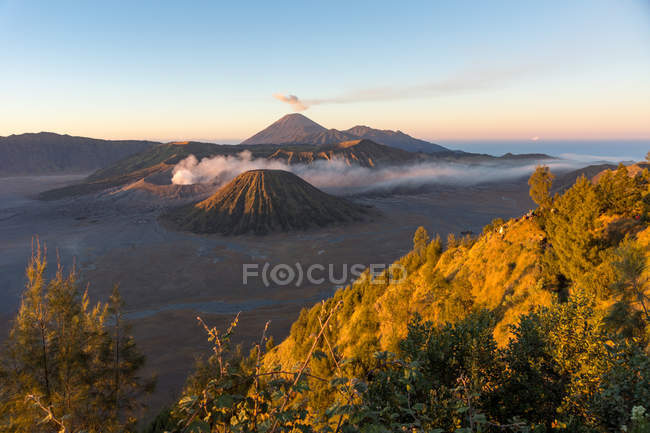 Indonésia, Java Timur, Probolinggo, cratera fumadora de Bromo com Batok, vulcão Semeru ao fundo sob a luz do pôr do sol — Fotografia de Stock