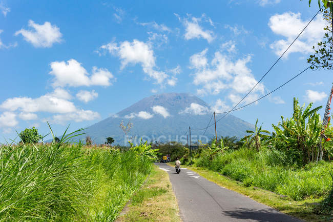 Индонезия, Бали, Карангасем, зеленый пейзаж со скутером на дороге к вулкану Агунг — стоковое фото