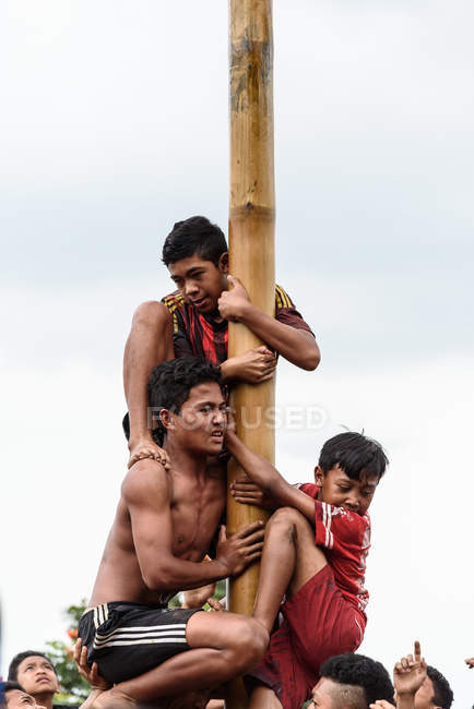 KABUL BULELENG, BALI, INDONESIA - 17 DE AGOSTO DE 2015: Adolescentes del pueblo trepan sobre un poste de madera engrasado . - foto de stock