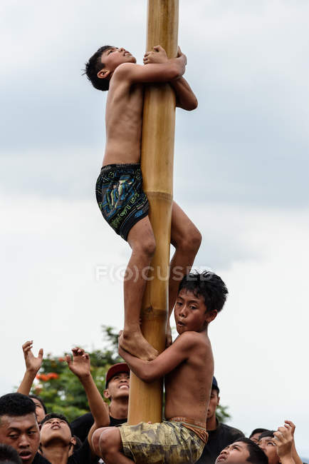 Кабул Buleleng, Балі, Індонезія - 17 серпня 2015: Підлітки від села, піднявшись на змащений дерев'яний стовп — стокове фото
