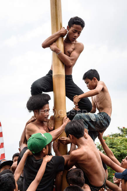 KABUL BULELENG, BALI, INDONESIA - AUGUST 17, 2015: Teenagers from village climbing on greased wooden pole — Stock Photo