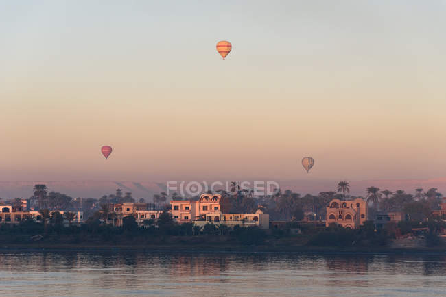 Vista lejana de casas cerca de globos fluviales y aéreos, Luxor, provincia de Luxor, Egipto - foto de stock