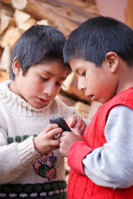 Garçons jouant avec un téléphone portable dans le village de Munaychay, Urubamba, Pérou — Photo de stock