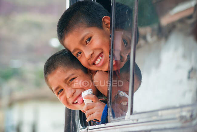Two children laughing out of window, Munaychay, Urubamba, Peru — Stock Photo