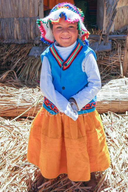 Местная маленькая девочка, стоящая на камышовом полу, озеро Титикака, острова Урос, Перу — стоковое фото