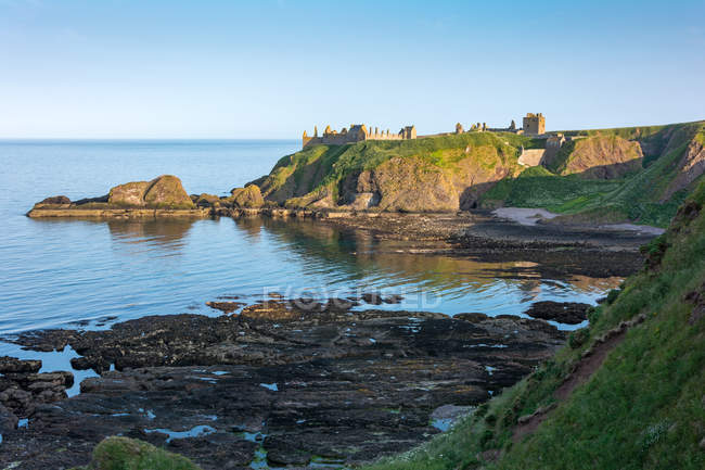 Великобритания, Шотландия, Абердиншир, Стоунхейвен, руины замка Данноттар на прибрежной скале под вечерним солнцем — стоковое фото