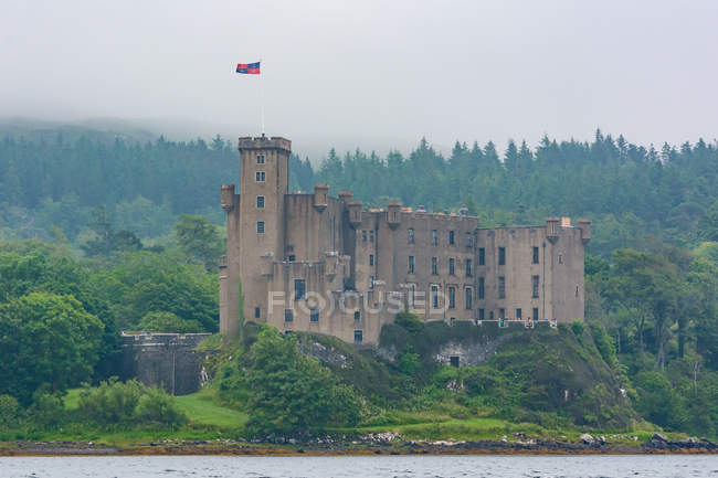 Royaume-Uni, Écosse, Highland, île de Skye, château Dunvegan dans les collines verdoyantes de la forêt au bord du lac — Photo de stock