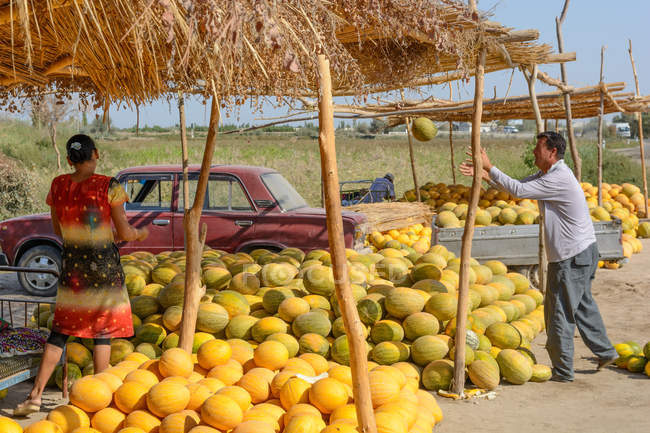 Uzbekistán, provincia de Buxoro, Jondor tumani, comerciantes de melón en carretera - foto de stock