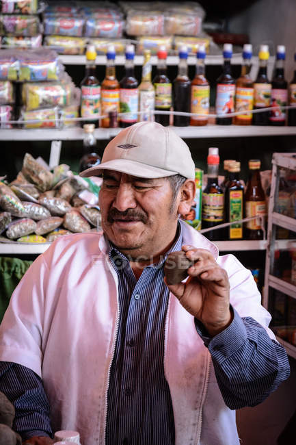 Взрослый продавец с картошкой в руке, рынок Арекипа, Арекипа, Перу — стоковое фото